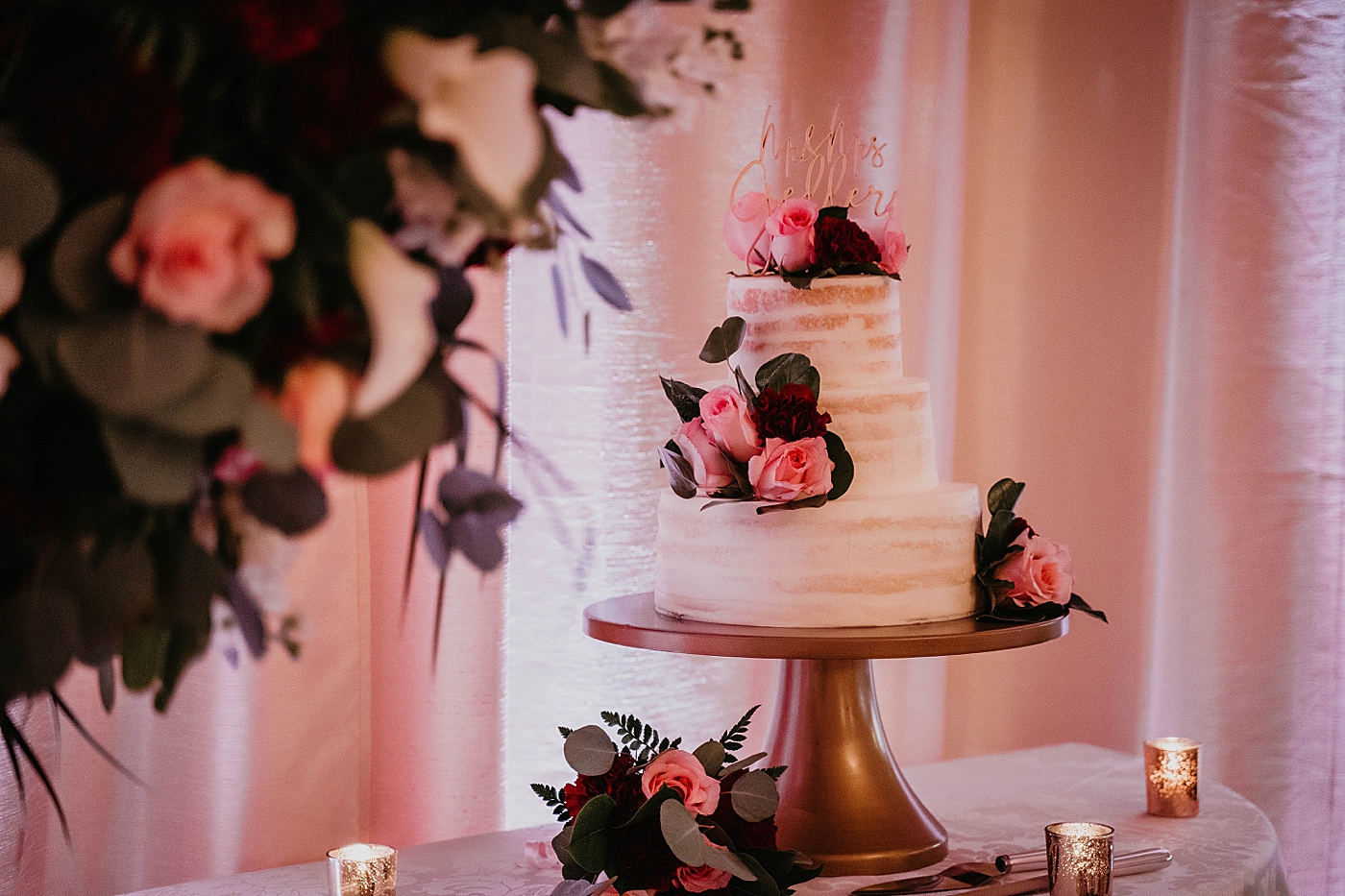 Detail shot of White fondant Wedding cake with pink and red flowers buds and stylish cursive wedding topper Romantic Winter Wedding captured NYC Wedding Planner Poppy and Lynn