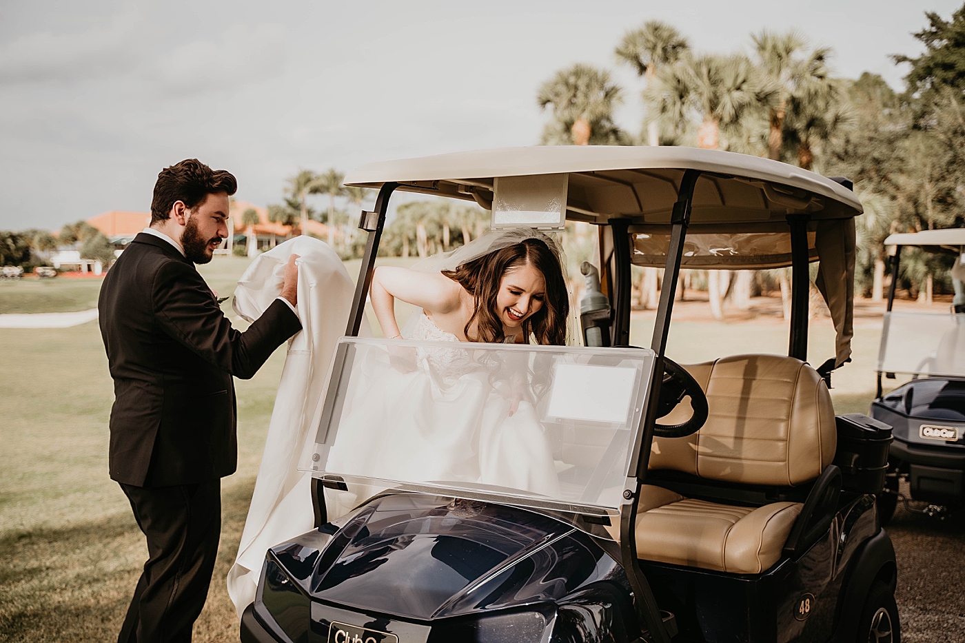 Bride getting on golf cart with Groom assisting holding train golf course palm trees Romantic Winter Wedding captured NYC Wedding Planner Poppy and Lynn