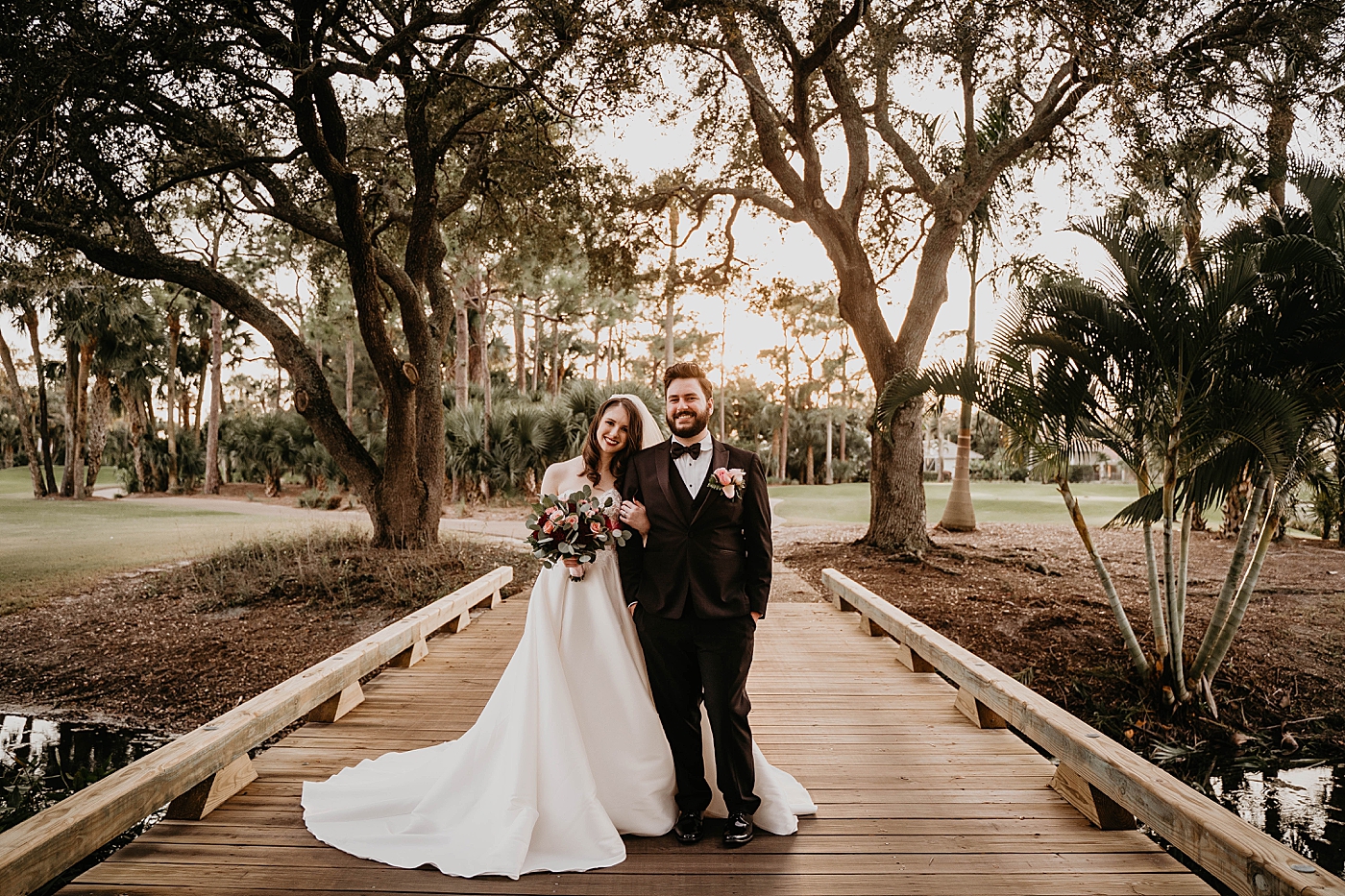 Bride holding Groom's arm on golf course Bridge with the sun setting on golf course Romantic Winter Wedding captured NYC Wedding Planner Poppy and Lynn
