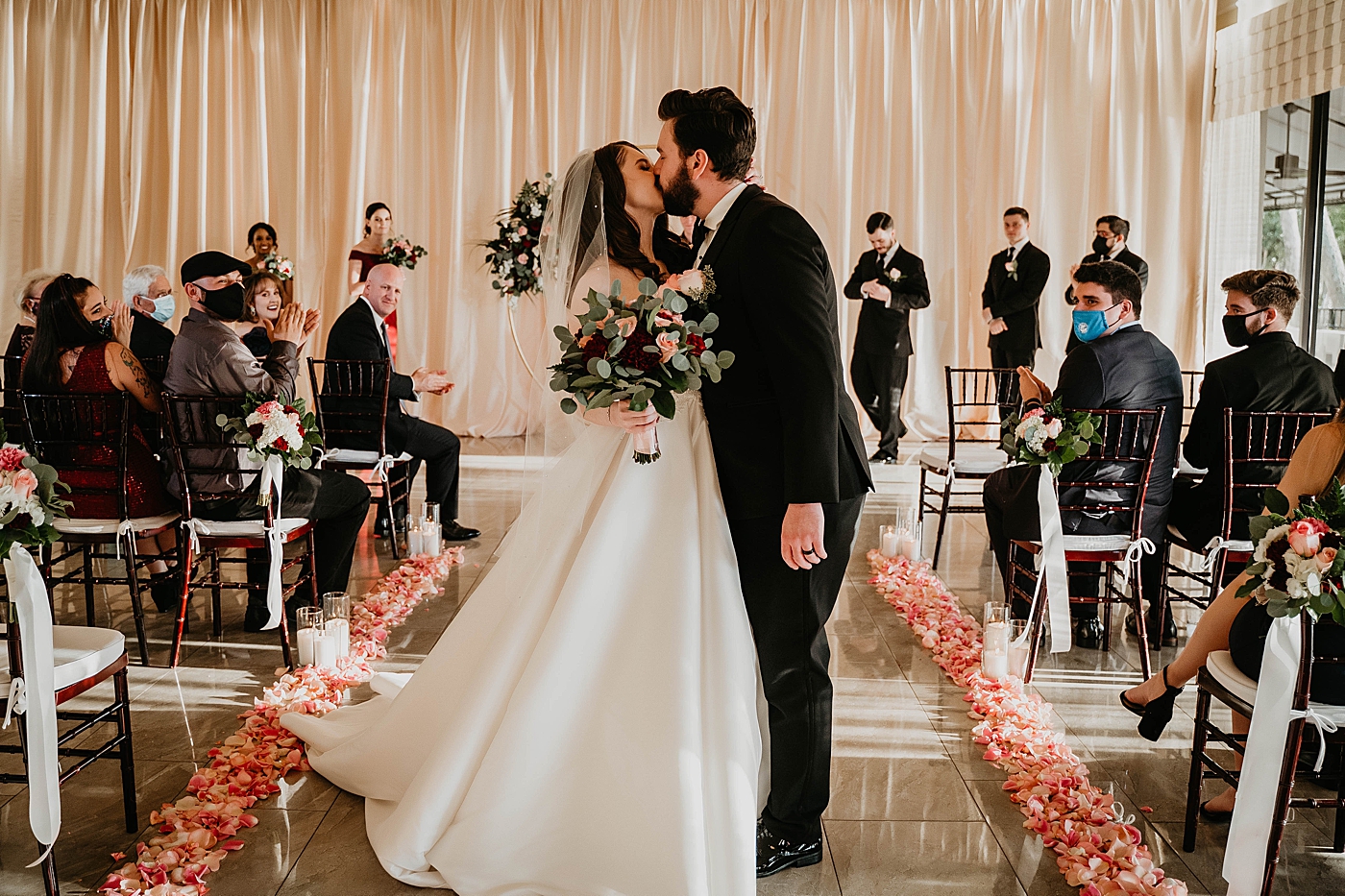 Wide shot of audience clapping and watching Bride and Groom exiting ceremony and kissing with floral aisle runner Romantic Winter Wedding captured NYC Wedding Planner Poppy and Lynn
