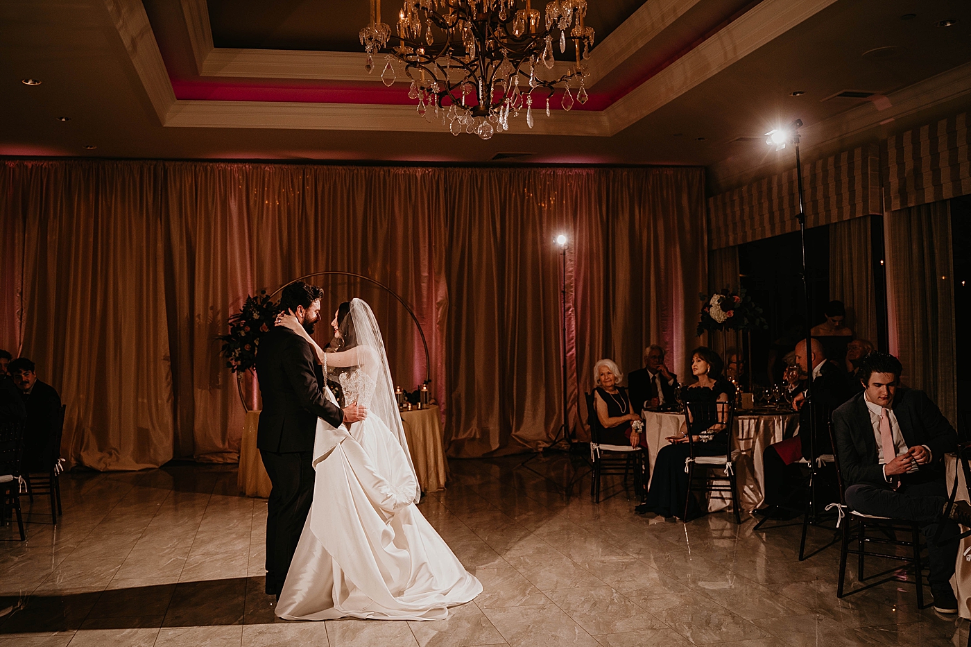 Warm lit first dance Bride and Groom with Family and Friends watching with vintage chandelier Romantic Winter Wedding captured NYC Wedding Planner Poppy and Lynn