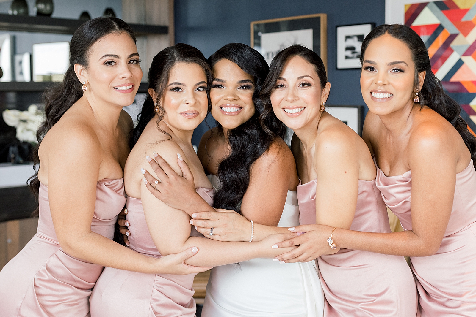 Bride and Bridesmaids hugging next to each other inside