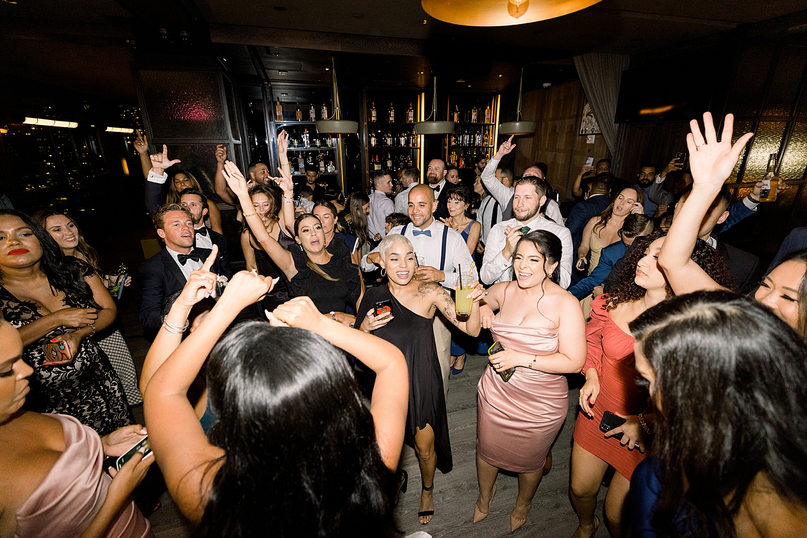 Guests dancing at wedding Reception at nighttime rooftop bar