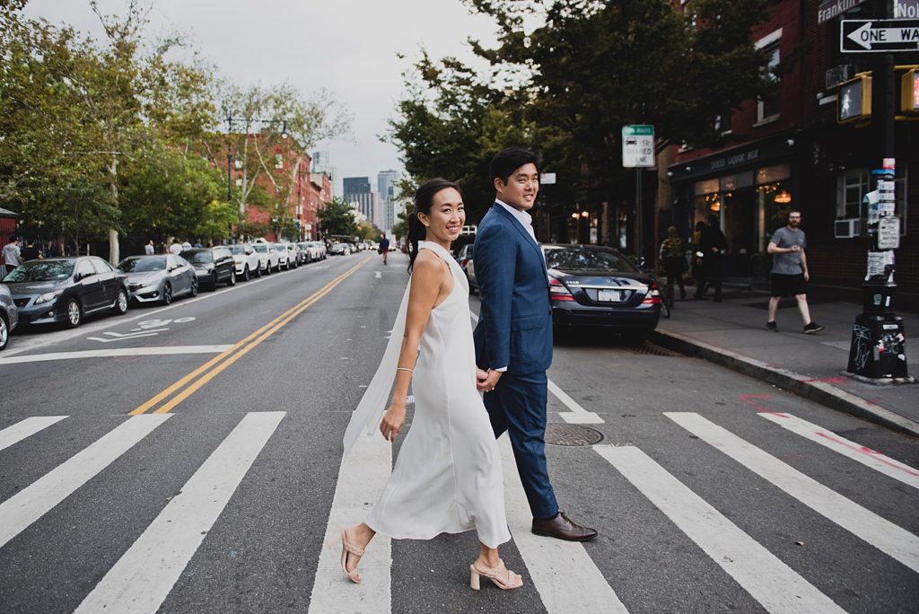 Couple holding hands and crossing Brooklyn street during the day