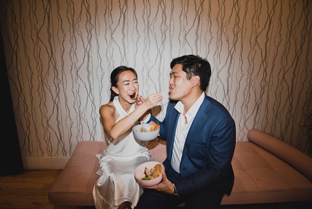 Couple sitting together and feeding each other food with chopsticks