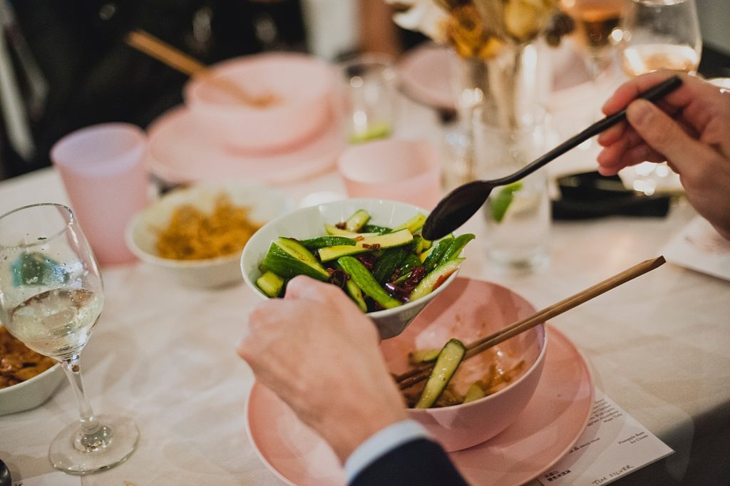 Closeup of guest scooping out of vegetable from bowl in family style Reception dinner