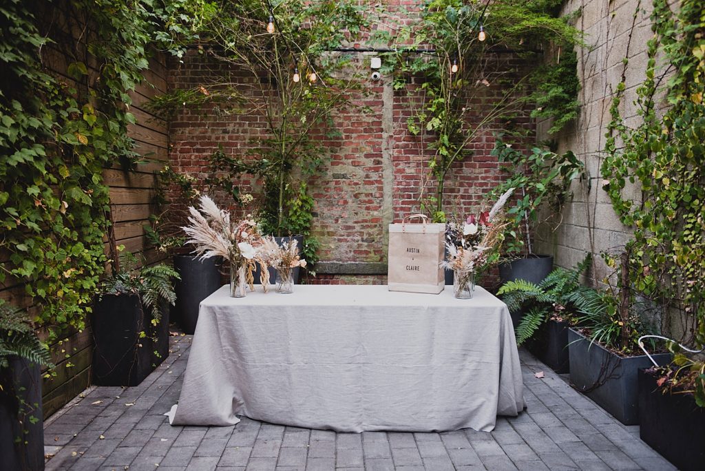 Detail shot of gift table in front of brick wall in courtyard with greenery