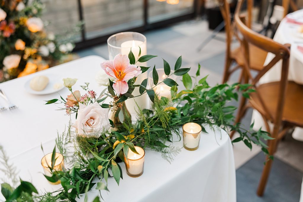 Detail shot of sweetheart table with greenery and flowers and candles