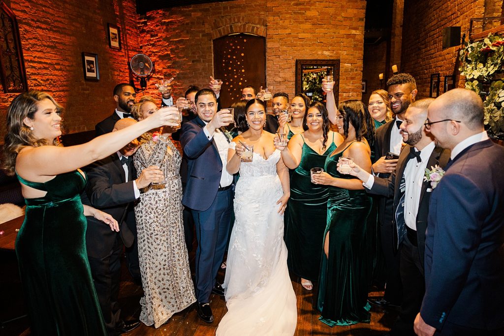 Bride and Groom with guests raising up glasses for a toast inside