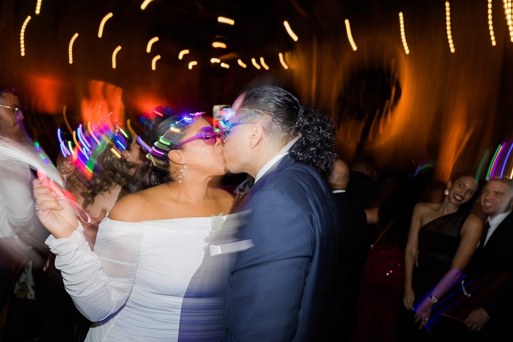 Candid shot of Bride and Groom kissing during lights and dancing for Hora Loca