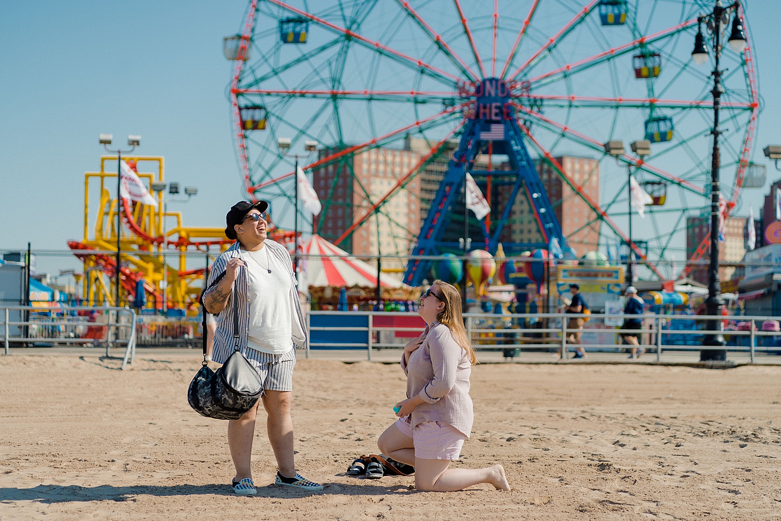 one woman proposing to other woman in front of coney island wonder wheel 