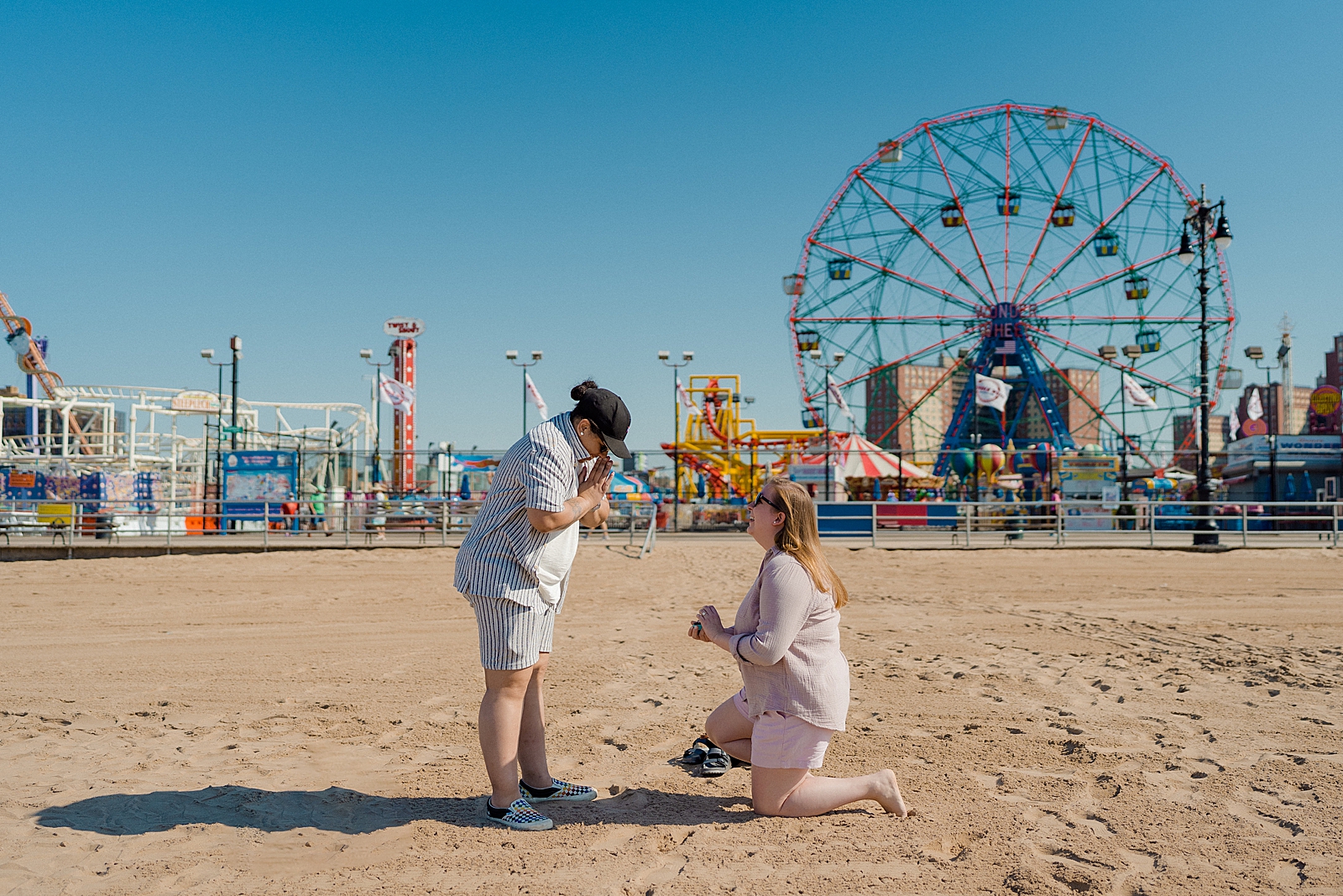 one woman proposing to other woman in front of coney island wonder wheel 