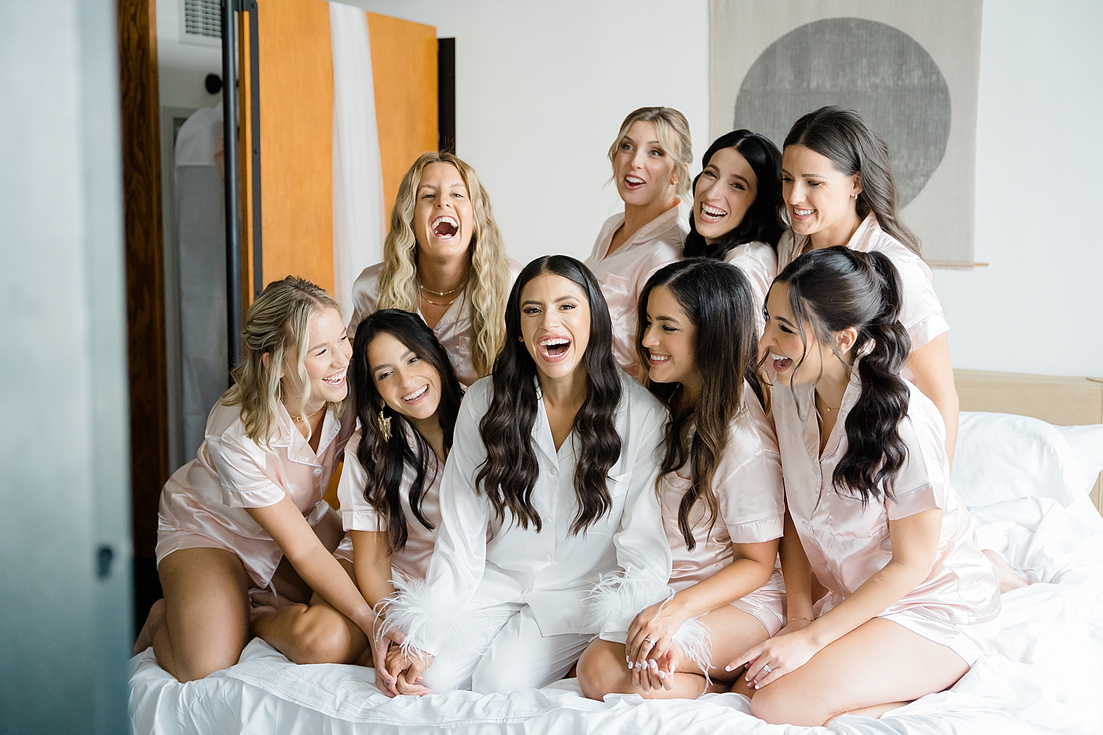 Shot of the bride and her bridesmaids smiling on a bed. 