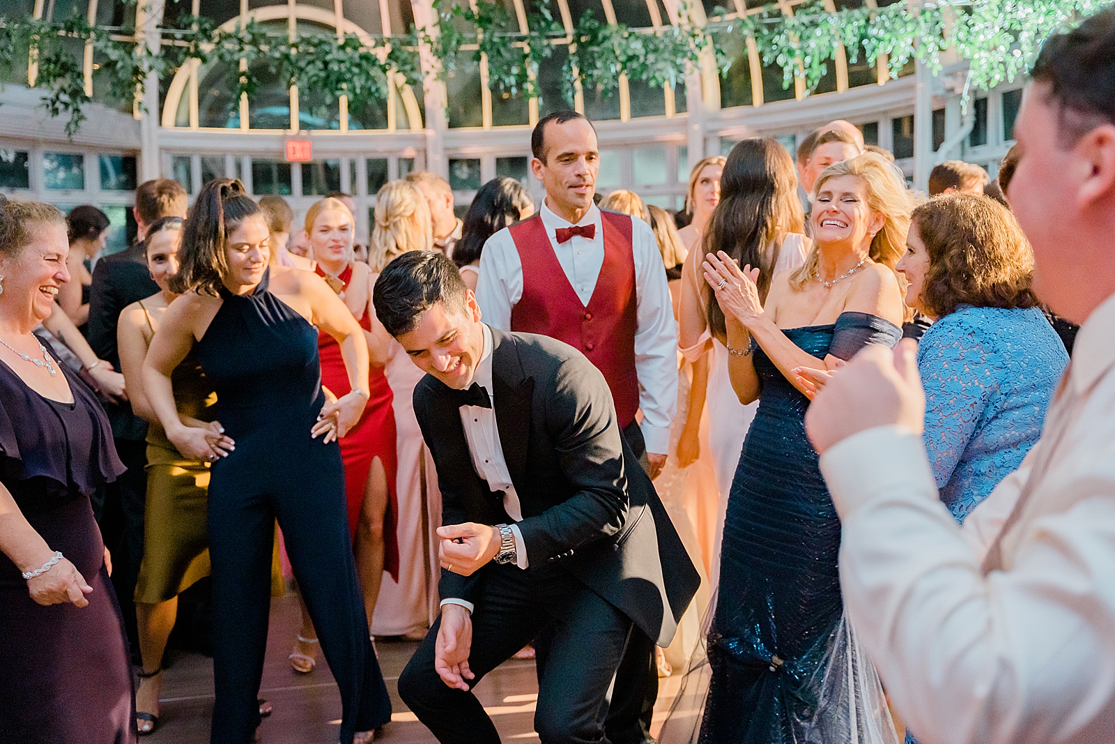 Shot of the groom dancing with family and friends on the dance floor. 

