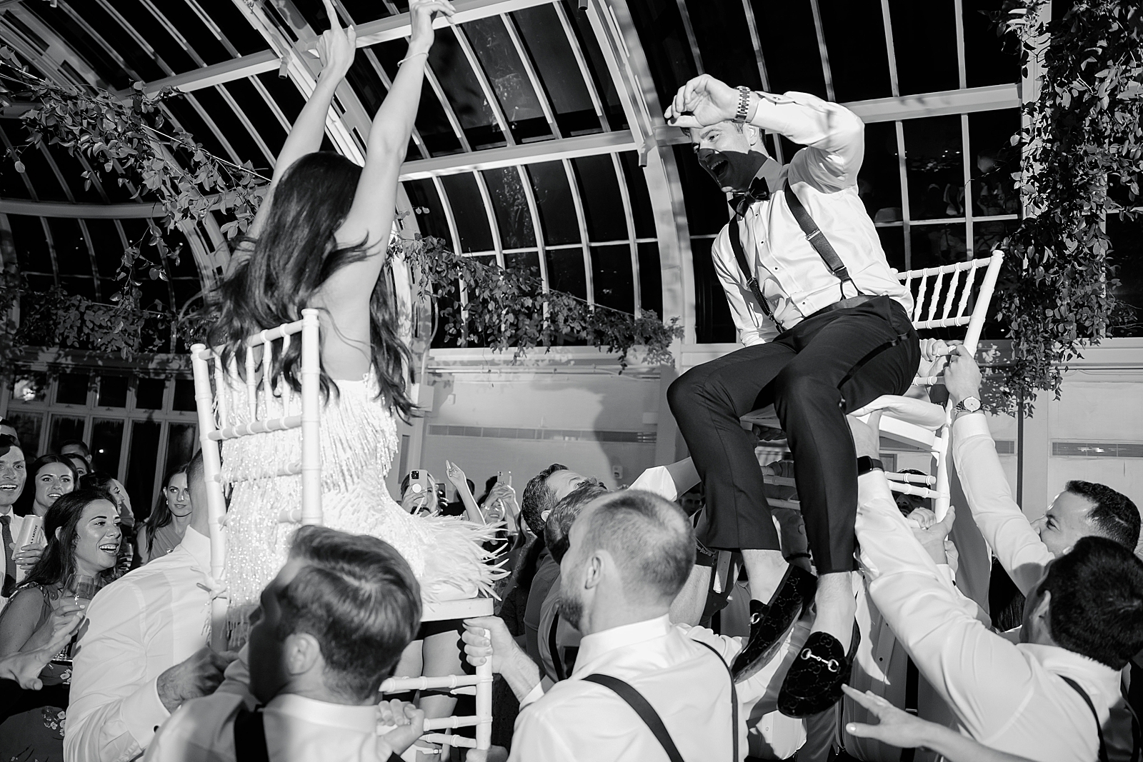 Shot of the bride and groom being lifted on chairs during the hora. 