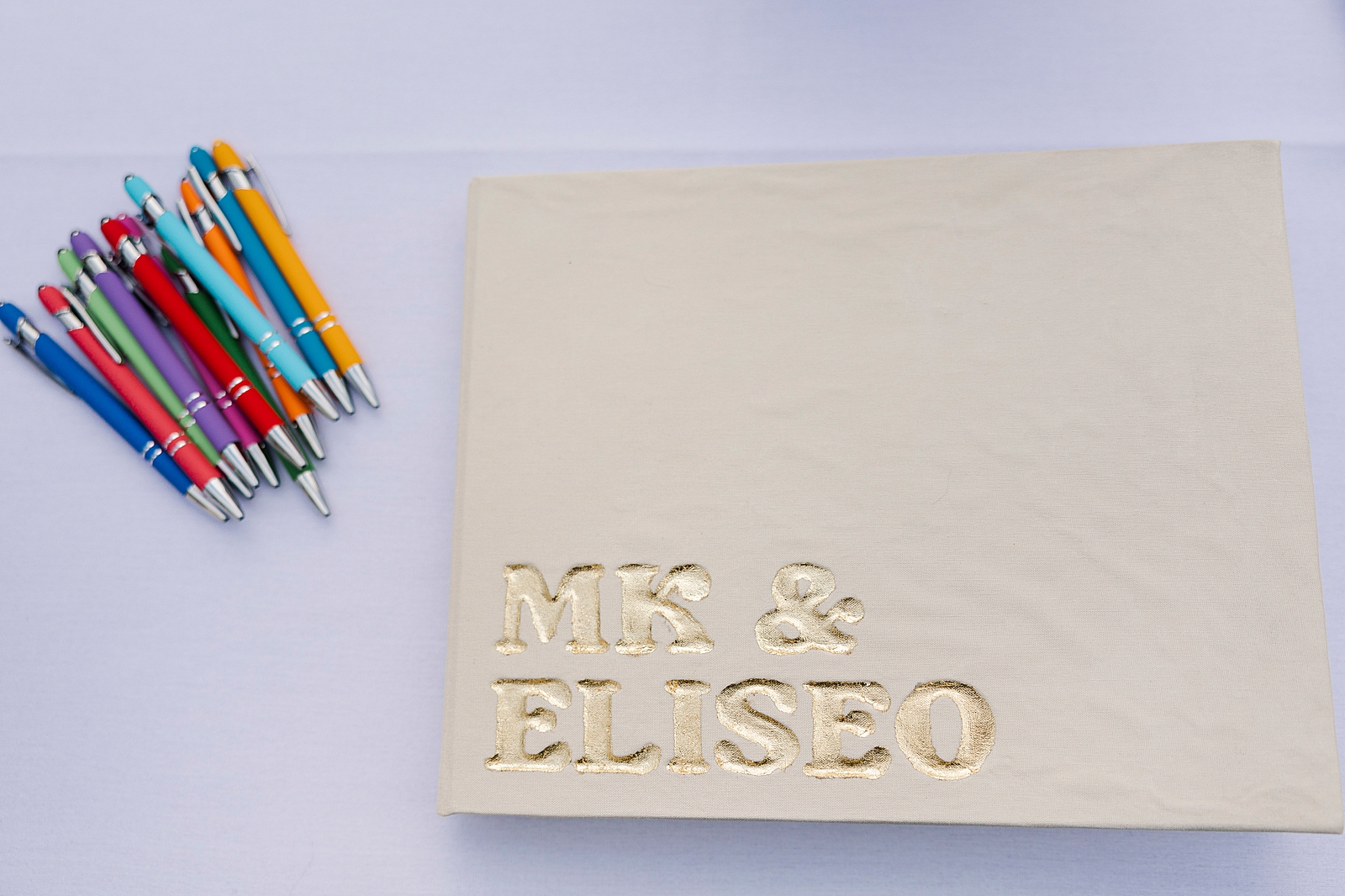 Shot of MK and Eliseo's wedding guestbook and several colorful pens. 