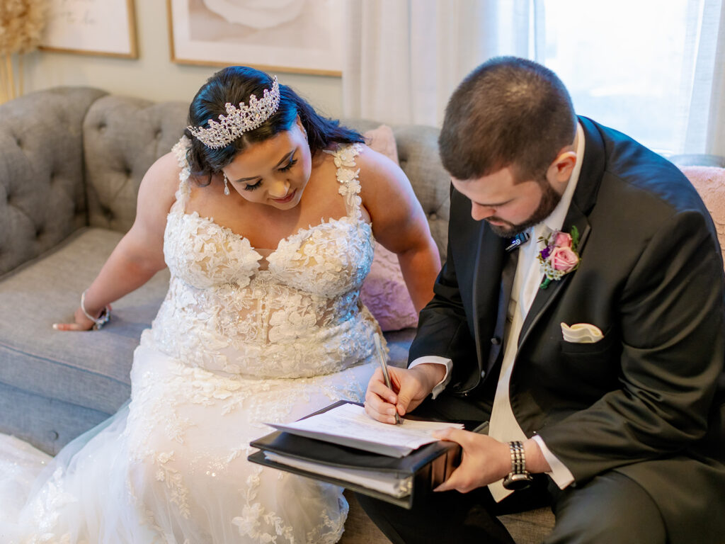 Shot of a couple sitting on a couch as they sign their marriage license. 