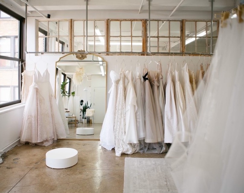 Interior shot of Carol Hannah, located in Midtown Manhattan. Shot features an open space with racks of hanging wedding dresses. 
