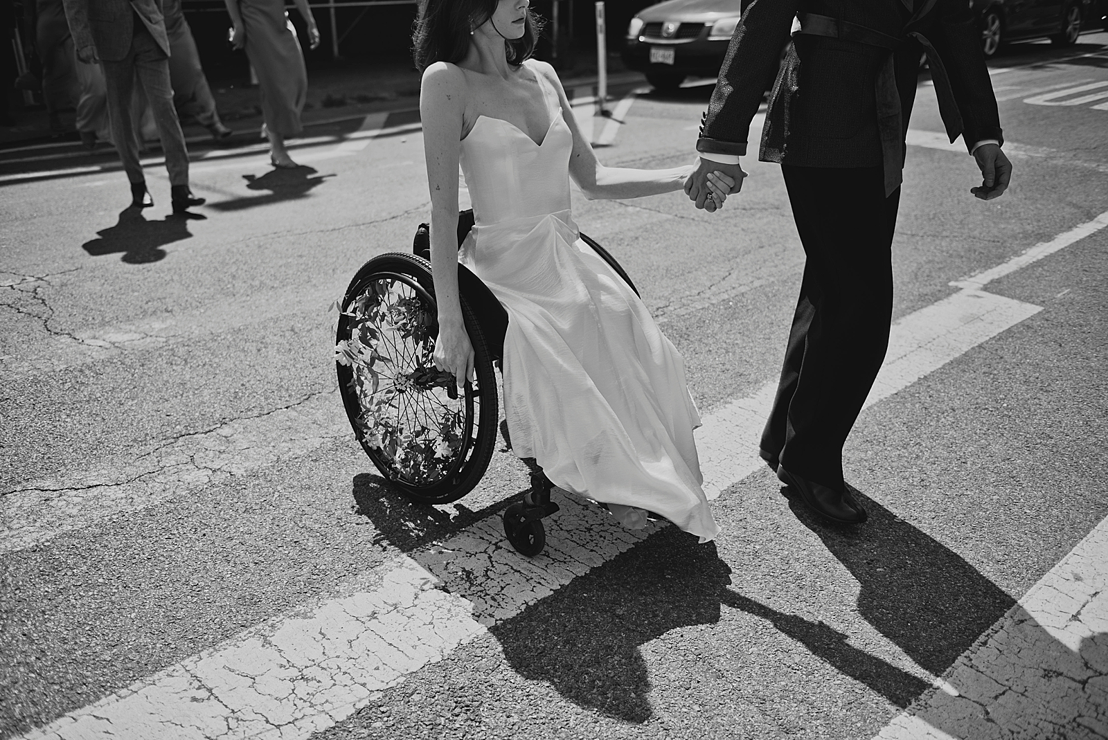 Black and white shot of the bride and groom holding hands as they make their way across a cross walk. 