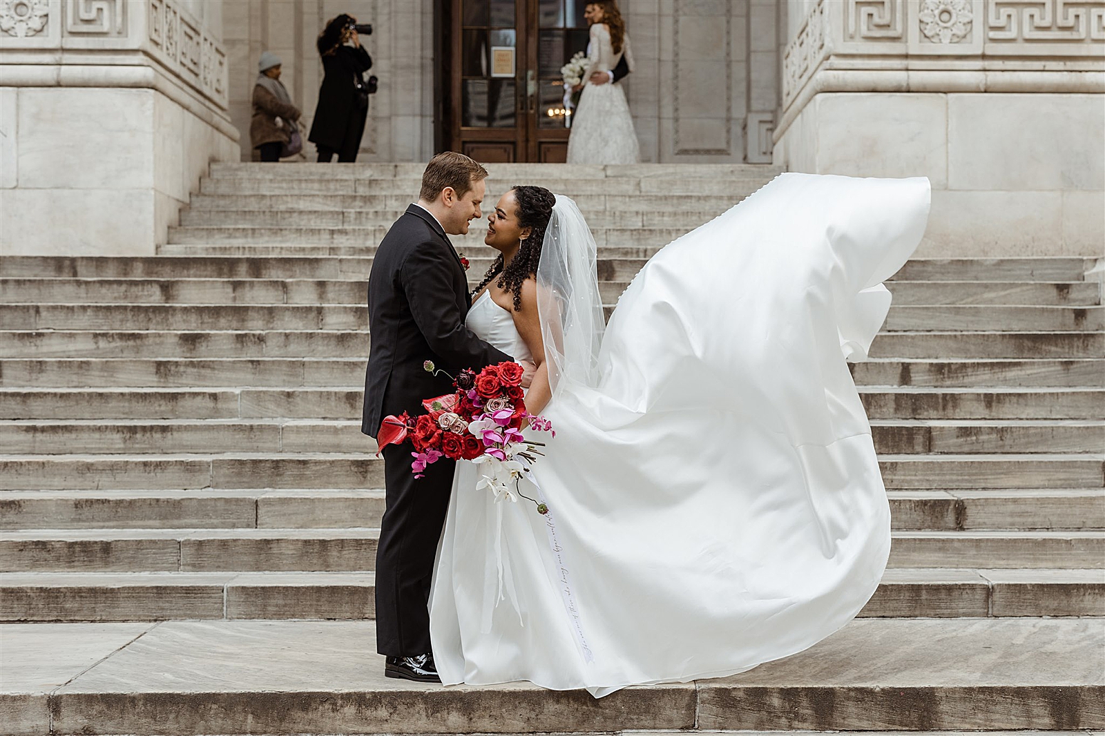 Bride and Groom are all smiles as they embrace on the steps of the New York Public Library.