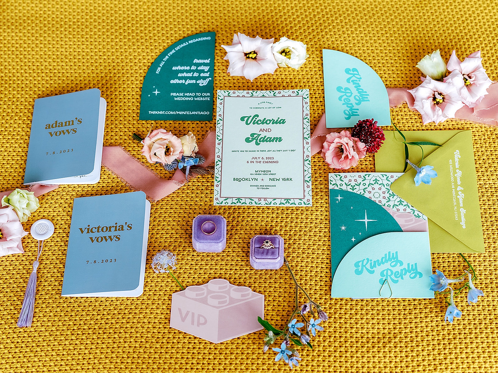 Up close shot of the colorful details including rings, vow books, and invitations. 