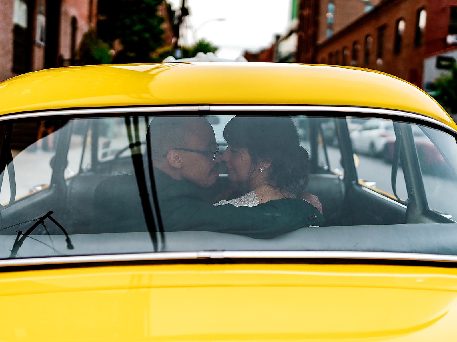 Shot of the bride and groom in a taxi posing nose to nose.