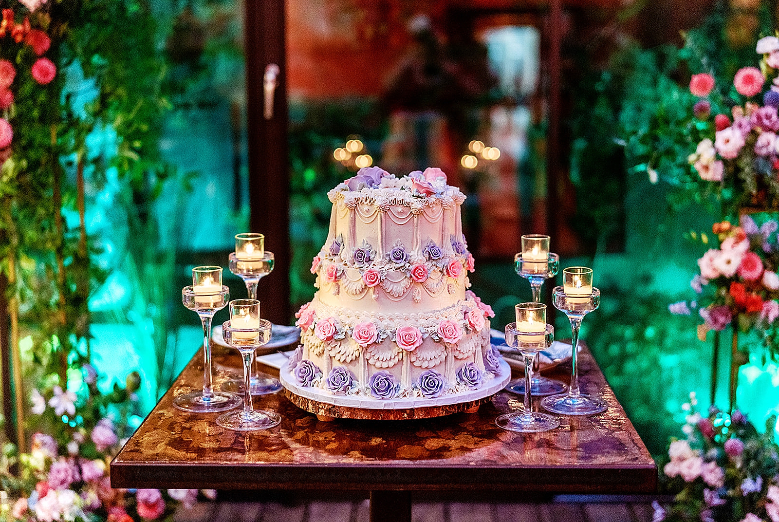 Full shot of the white, pink and purple wedding cake being presented on a table.