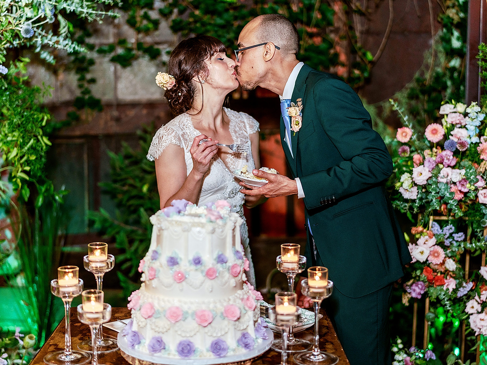 Shot of the bride and groom sharing a kiss behind their wedding cake. 