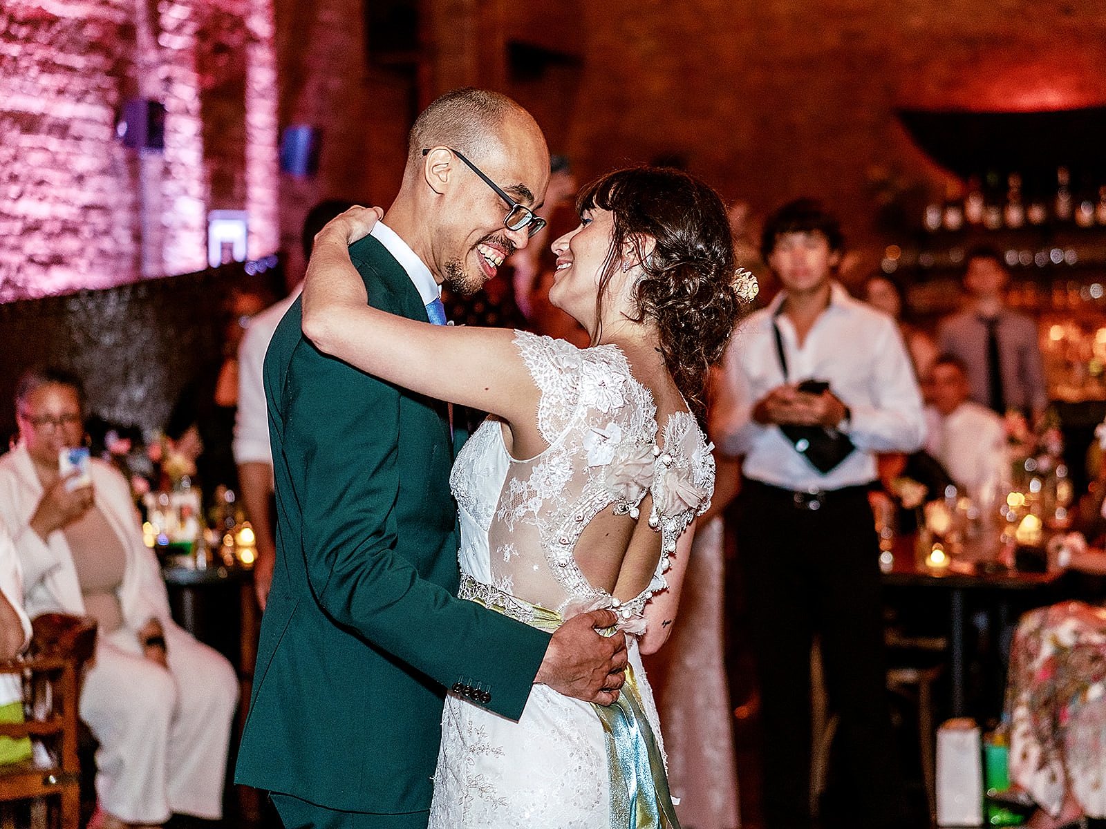 Shot of the bride and groom being all smiles as they share in an embrace during their first dance. 