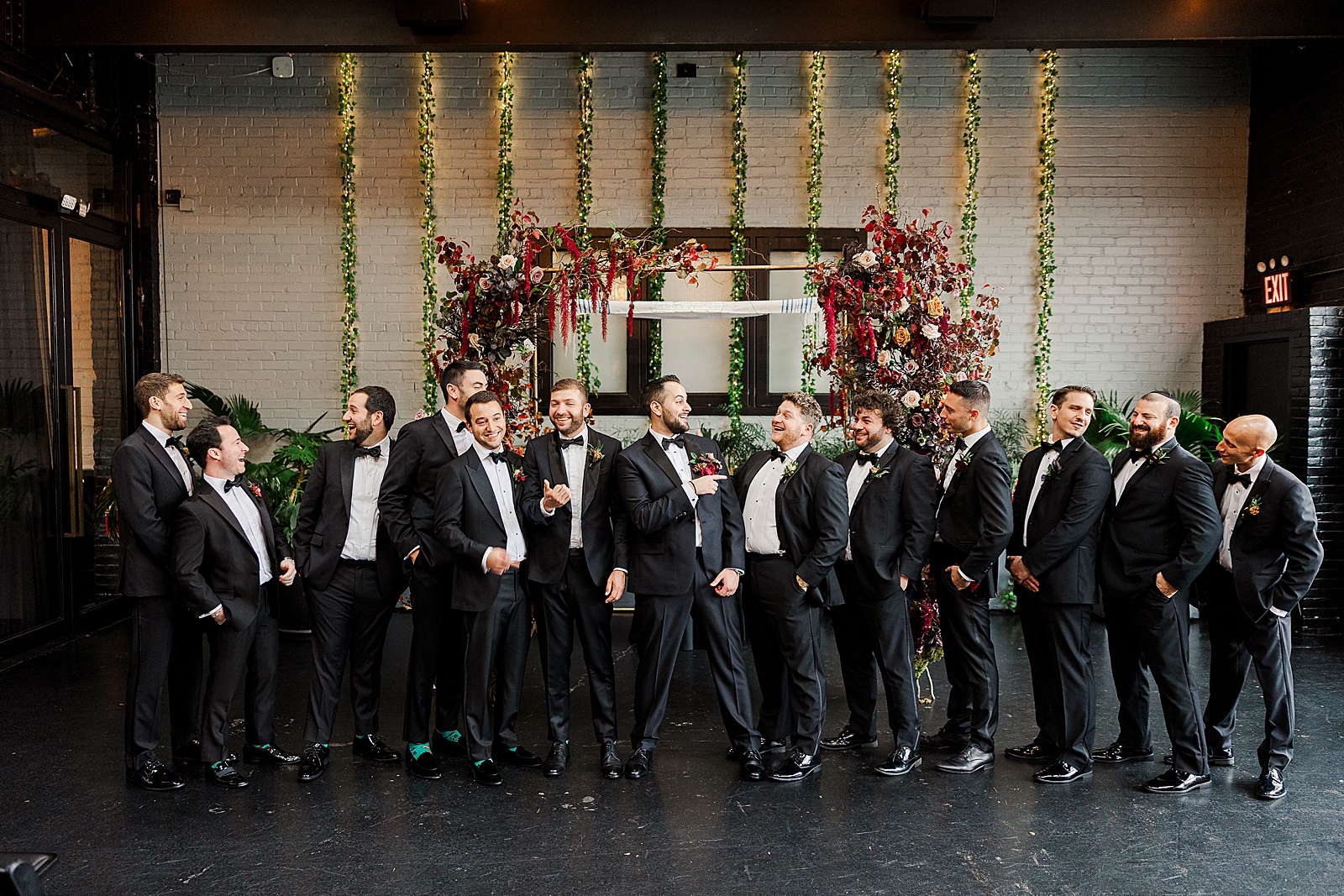 Full shot of the groom and his groomsmen posing in front of the ceremony chuppah. 