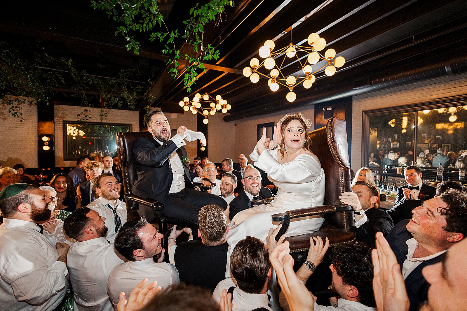 Shot of the Bride and Groom being lifted in chairs by their friends and family during the Hora. 