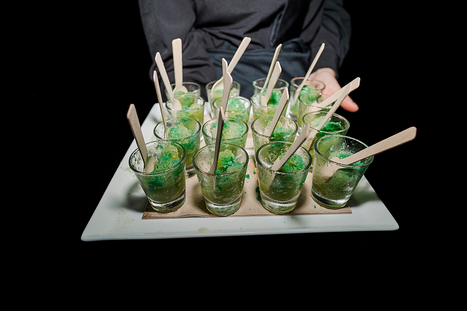 Close up shot of green dessert being served in individual shot glasses. 