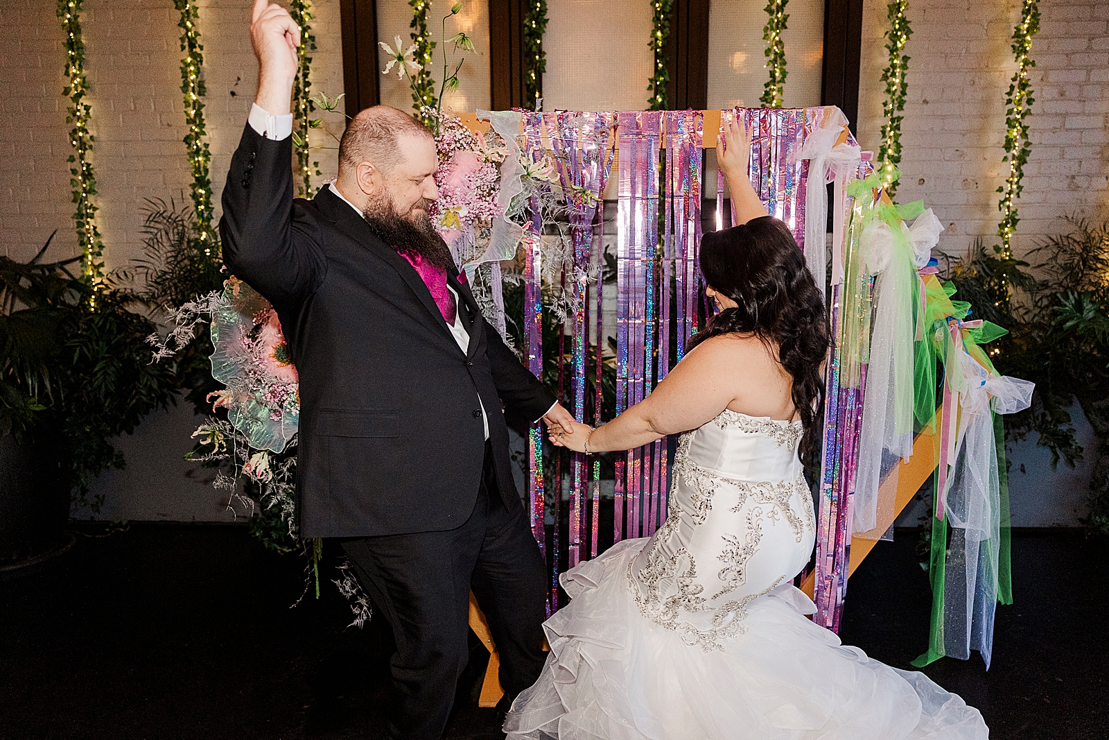 Shot of the bride and groom dancing in front of the hexagon shaped ceremony arch. 