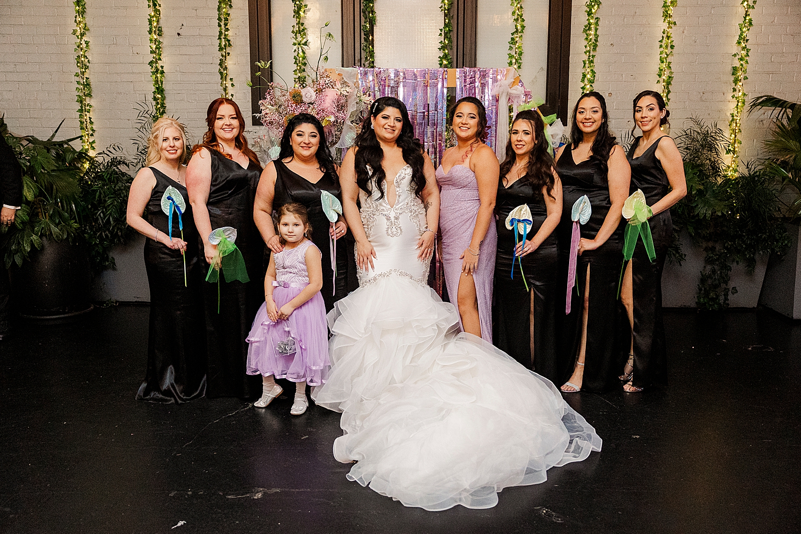 Shot of the bride, her bridesmaids, and the flower girl posing in front of the hexagon shaped ceremony arch. 