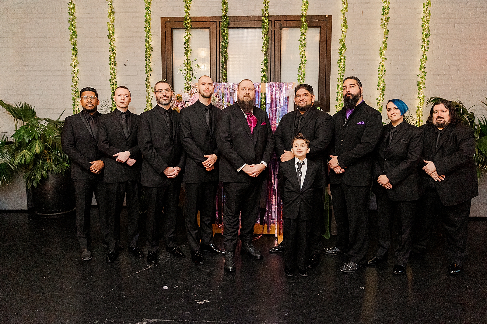 Shot of the groom, his groomsmen, and the ring bearer posing in front of the hexagon shaped ceremony arch.