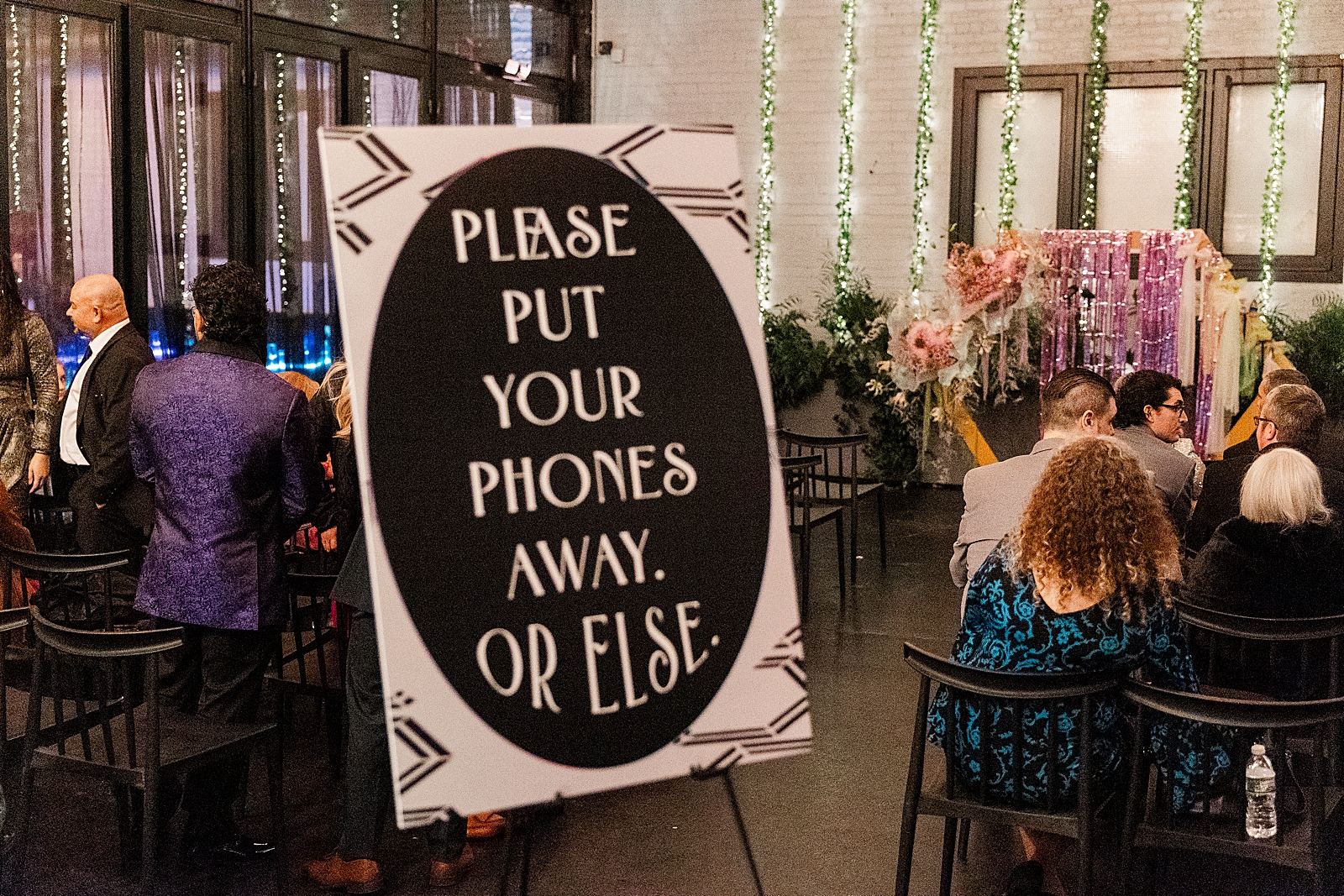 Shot of the ceremony space with a focus on a sign telling guests to put their phones away, "or else." 