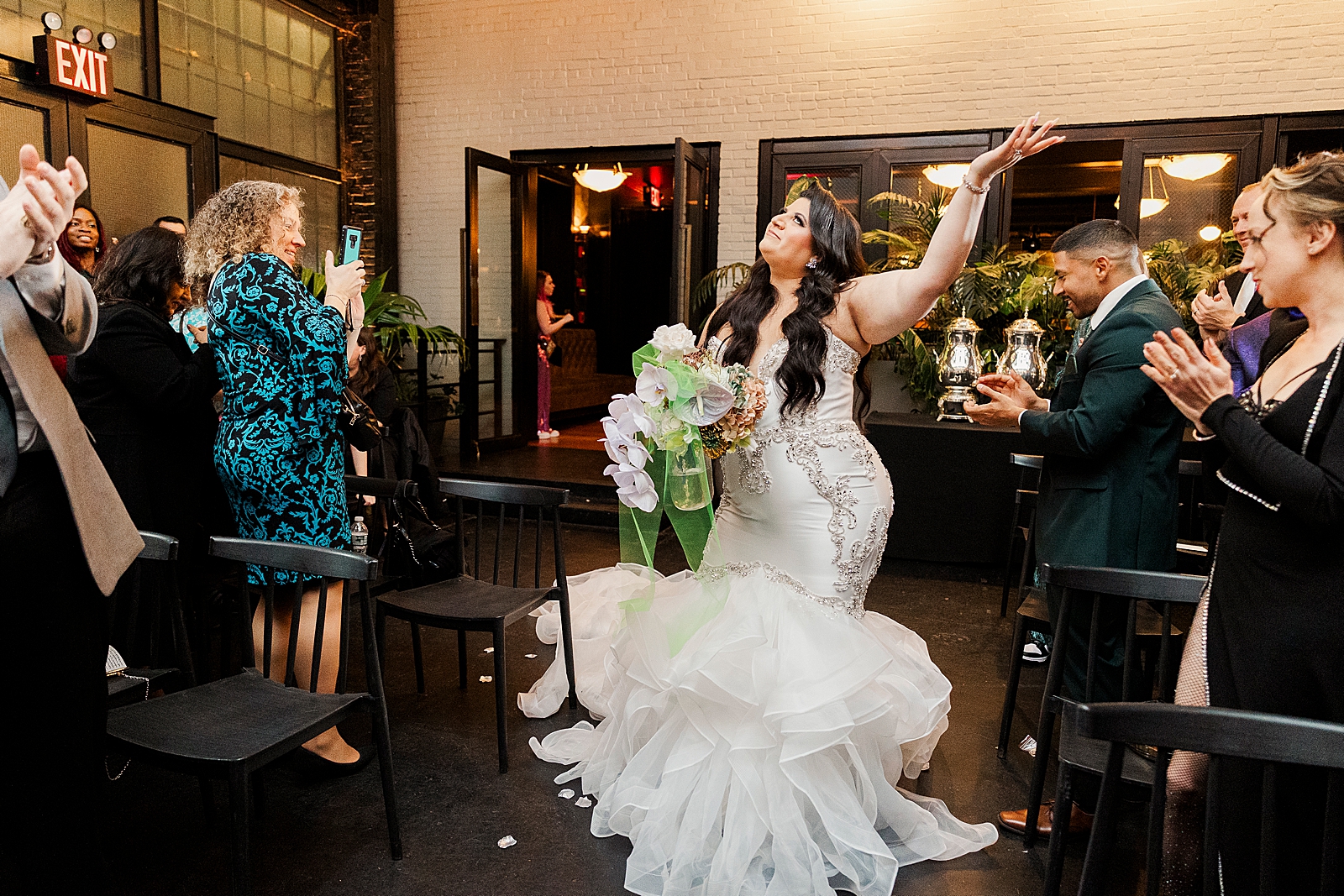 Shot of guests cheering as the bride makes her way down the aisle. 