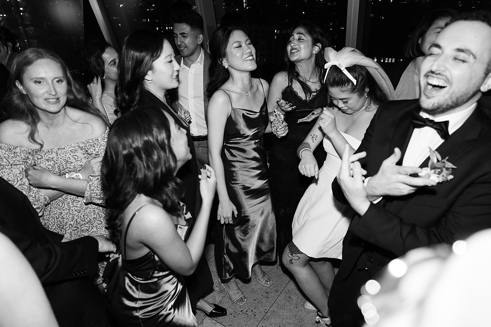 Black and white shot of the bride and groom on the dancefloor with their guests. 